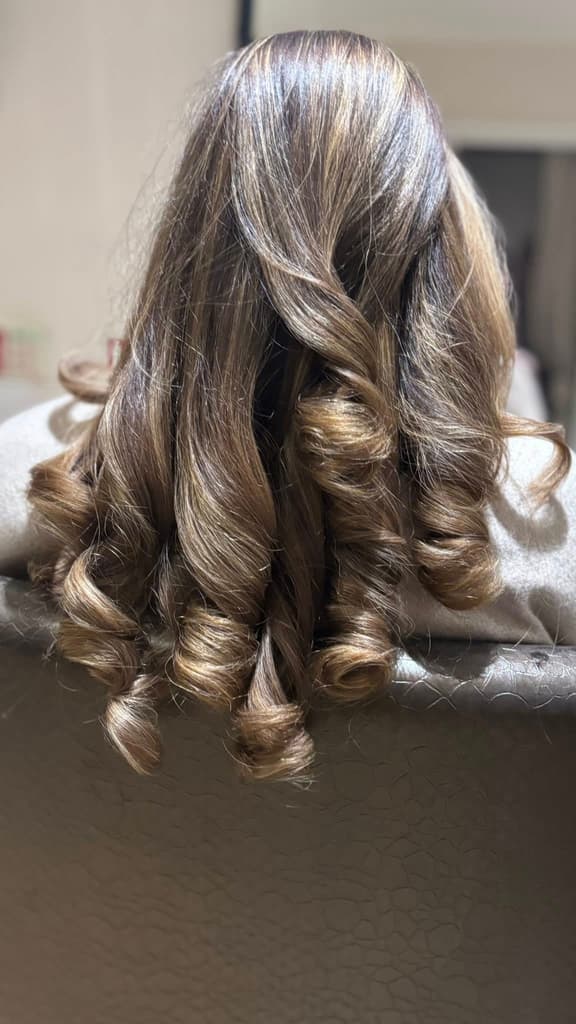 Long highlighted brown hair styled in voluminous curls at Chelsey's Hair, Blandford Forum