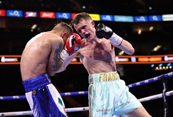 Frankie Wood throwing an uppercut at Callum Lee against the ropes