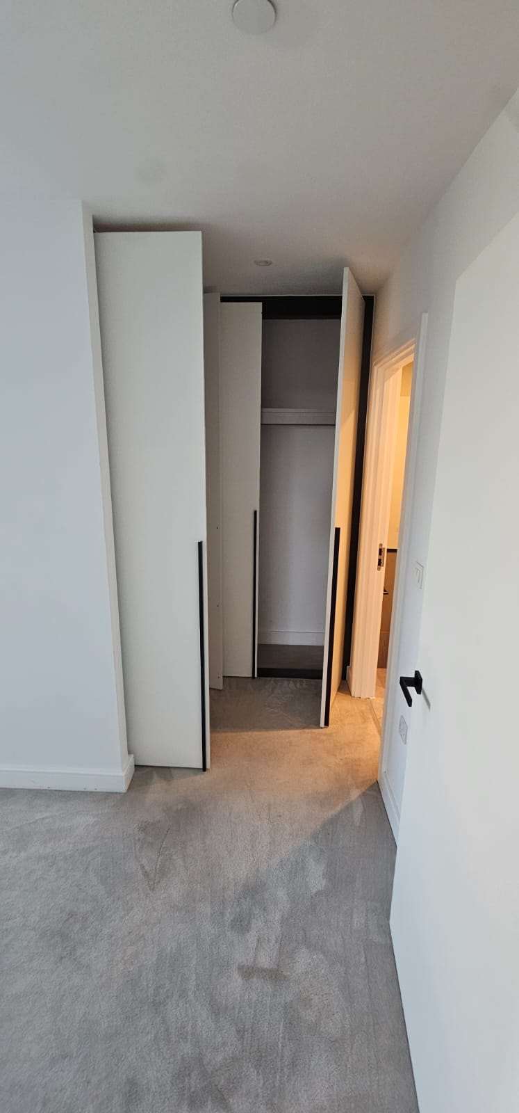 Cleaned grey bedroom carpet with vacuum lines beside an open white sliding wardrobe