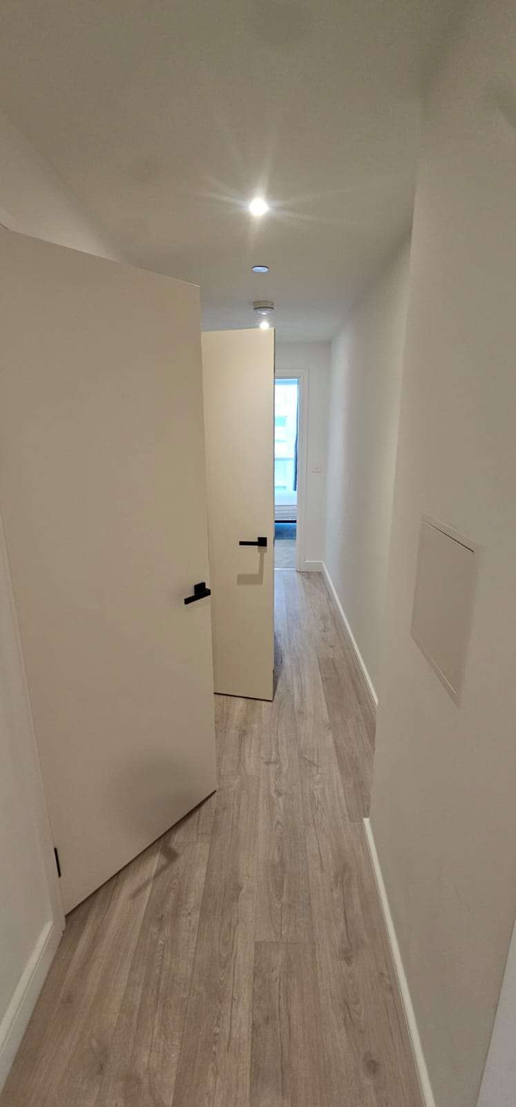 Clean empty hallway with wood-effect laminate flooring and white walls