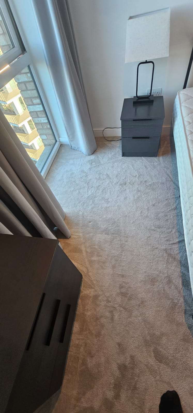 Freshly cleaned bedroom carpet with bedside drawers and mattress