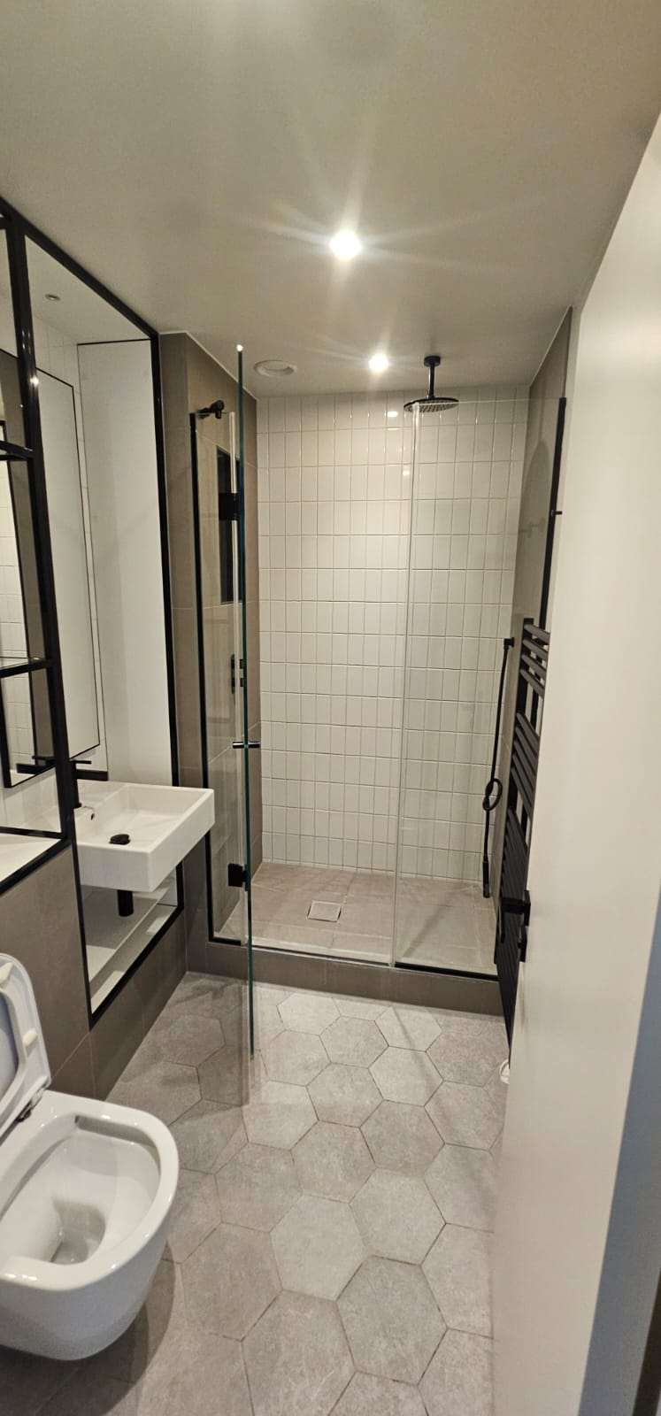 Clean modern bathroom with a walk-in tiled shower, wall-hung basin and toilet