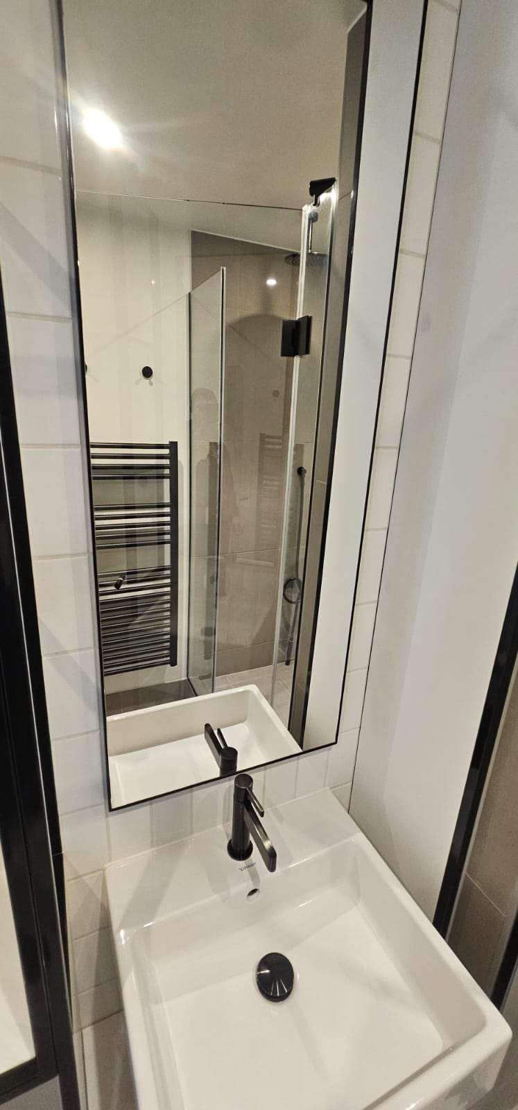 Clean compact en-suite bathroom with basin, mirror and shower