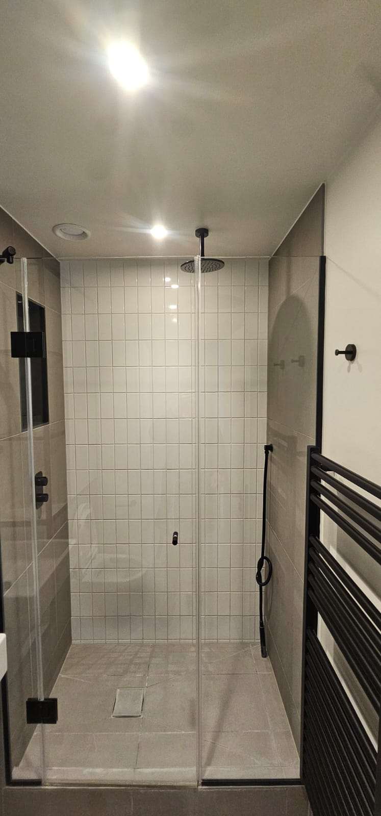 Clean tiled walk-in shower cubicle with glass screen