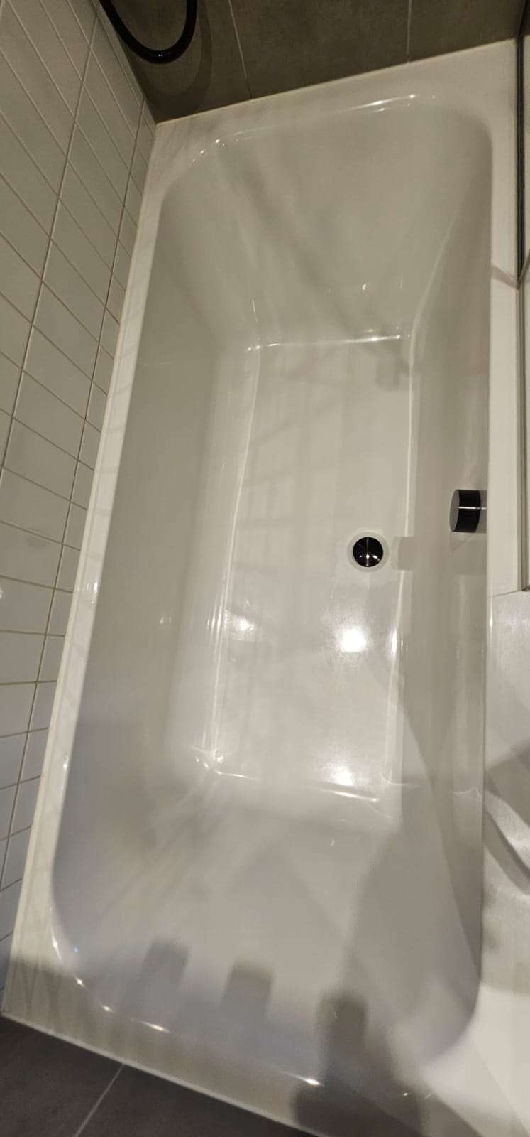 Clean white bathtub against white metro tiles