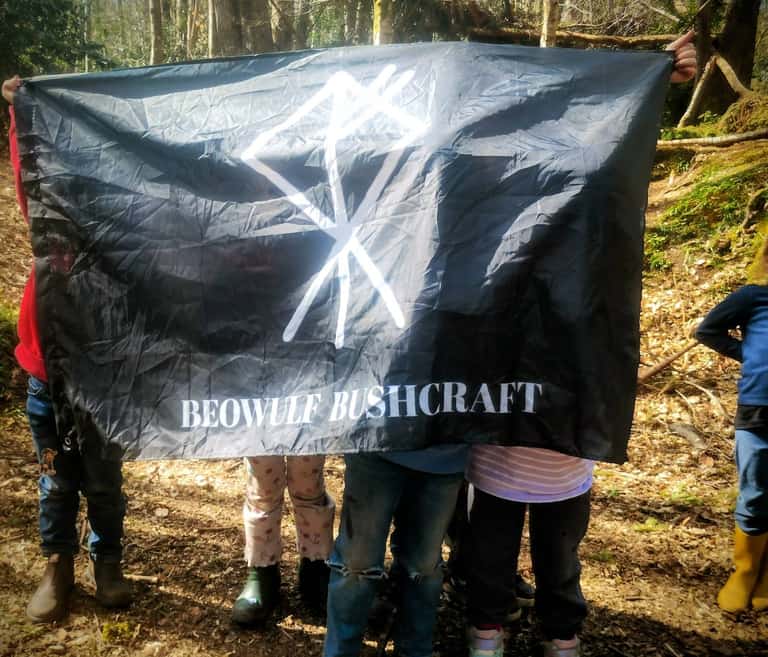 Participants holding the Beowulf Bushcraft flag at Greyfield Woodlands