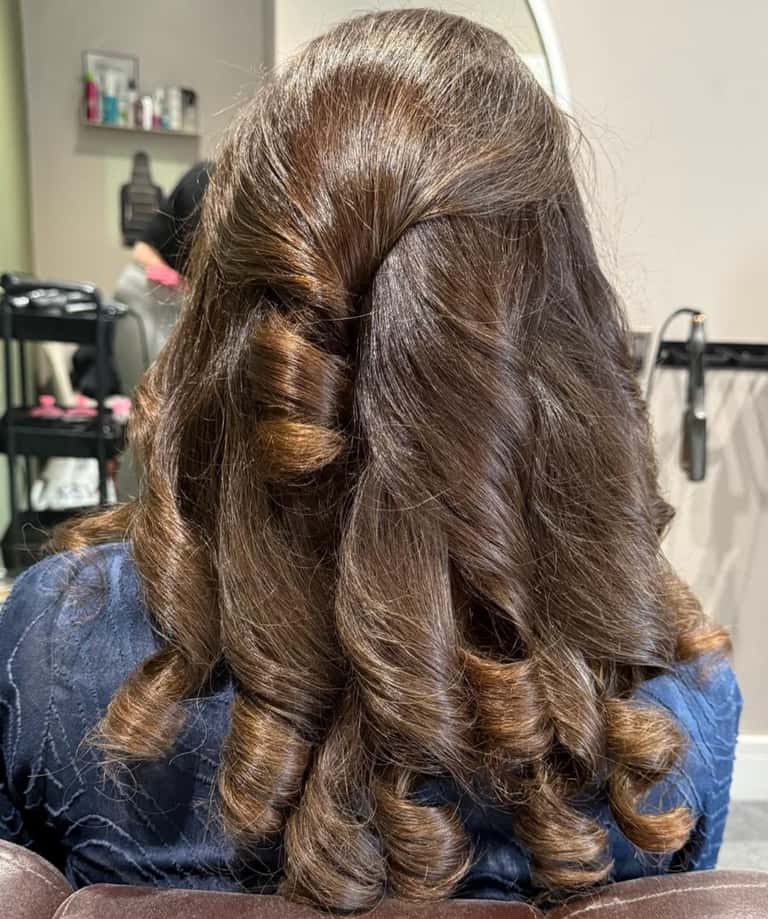 Long brown hair styled in a romantic half-up half-down look with bouncy barrel curls