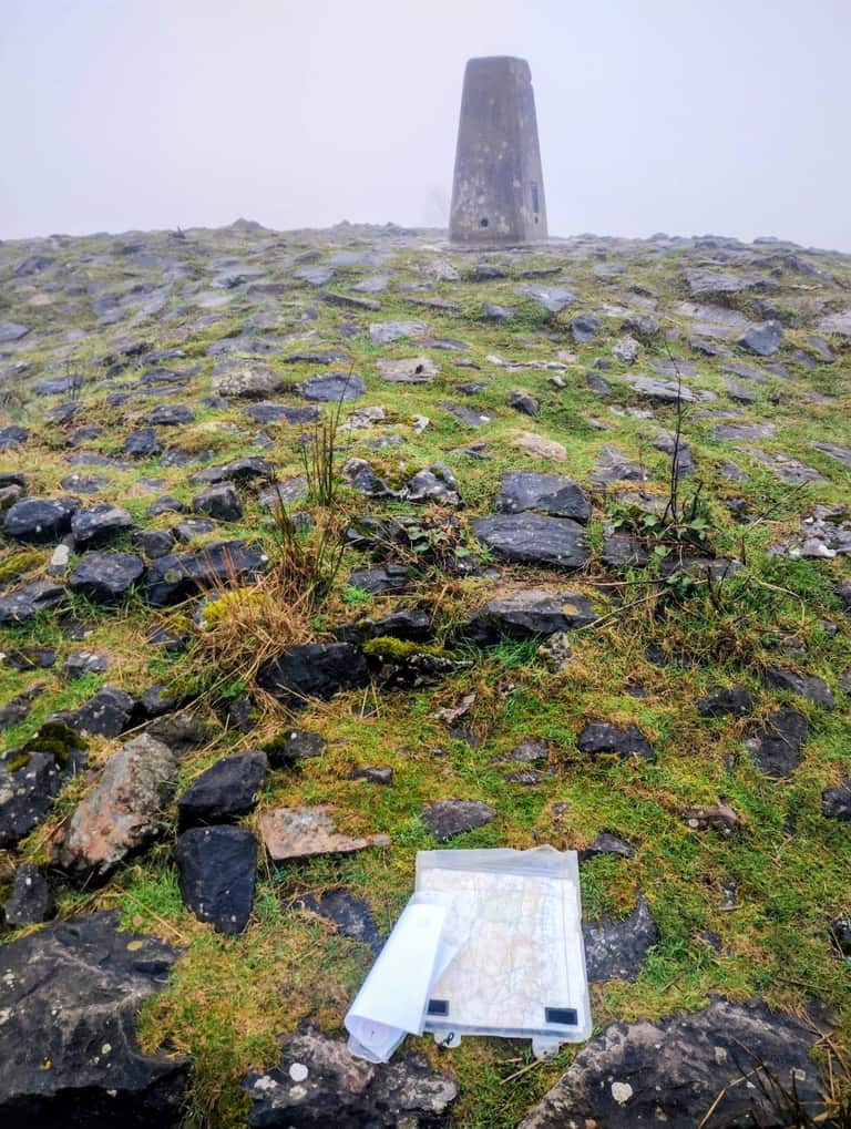 Concrete trig point on a hilltop with a map case