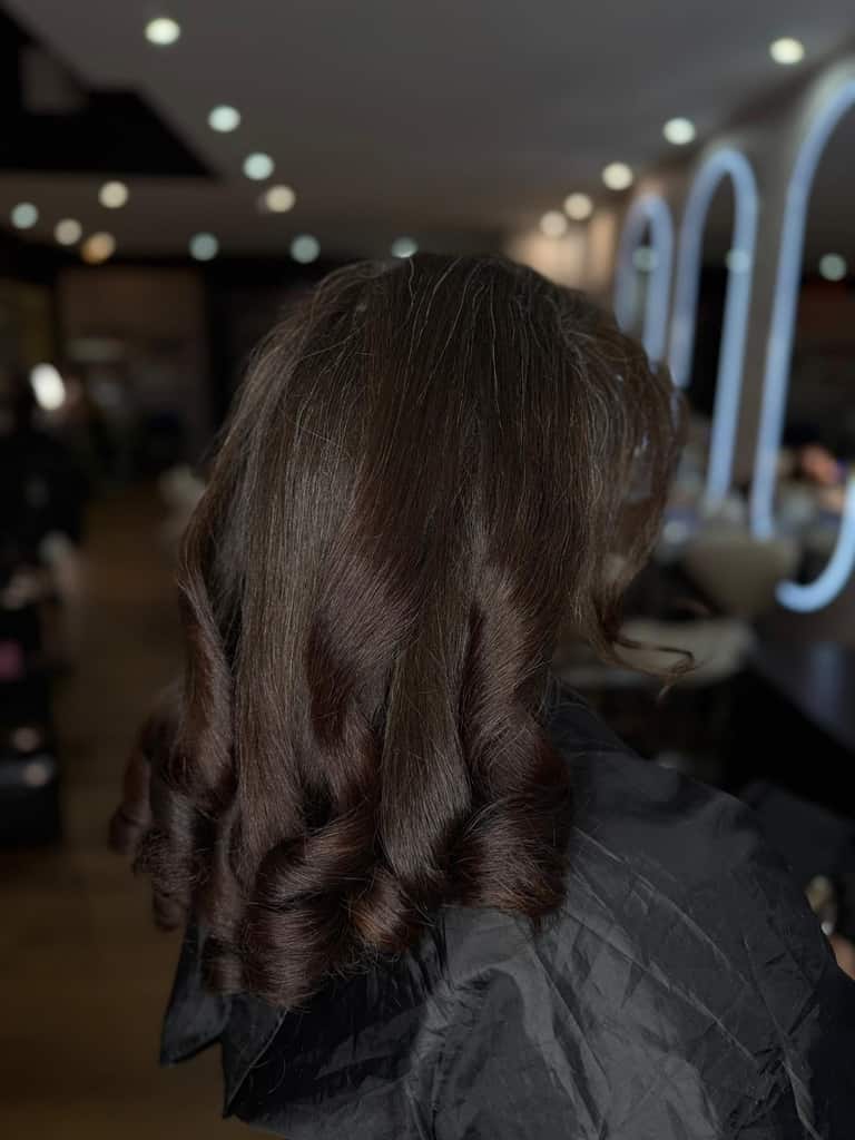 Medium-length dark hair with soft curls in the salon