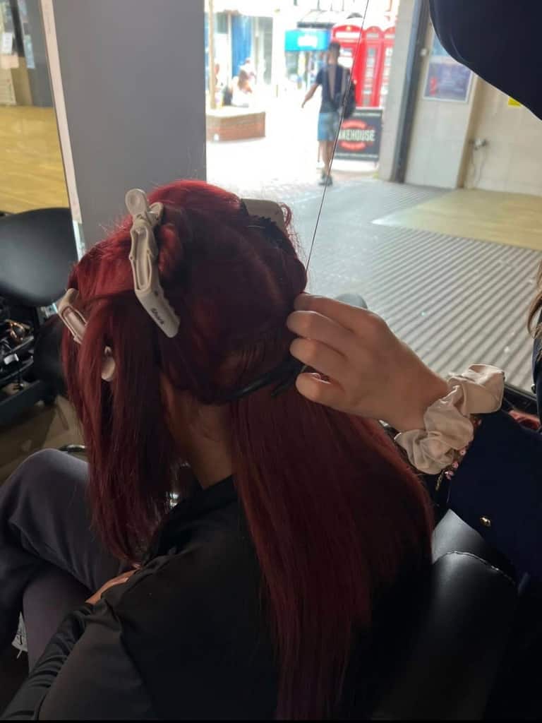 Red colour application in progress with hair sectioned and clipped