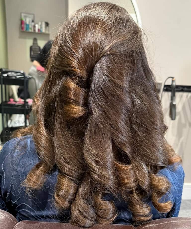 Long brown hair styled in a romantic half-up half-down look with bouncy barrel curls