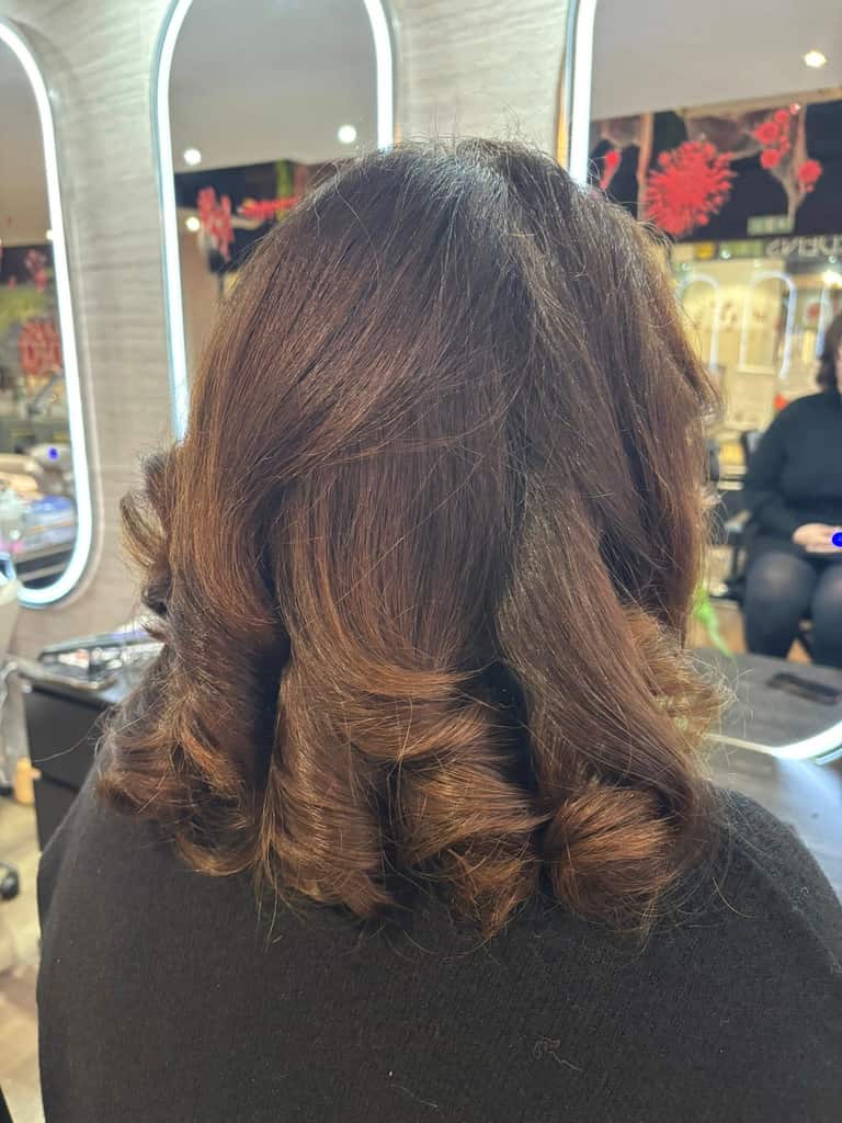 Medium-length brown hair styled with bouncy round-brush curls