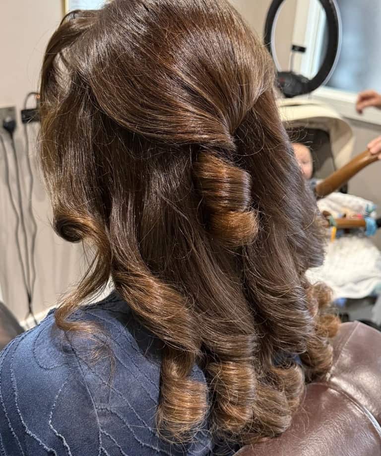 Long brown hair being curled with a styling tong at Chelsey's Hair