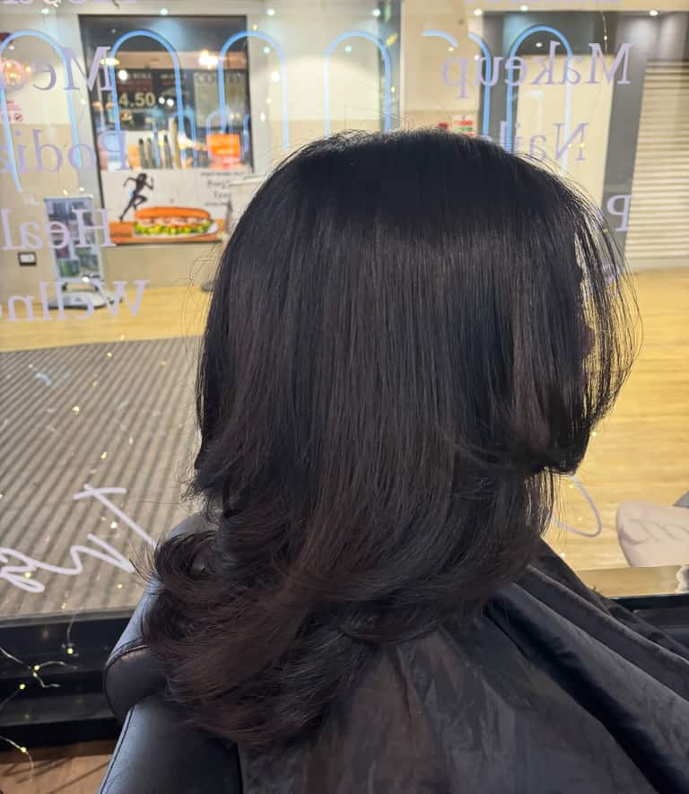 Dark brown hair styled in a 70s-inspired flicked blow-dry