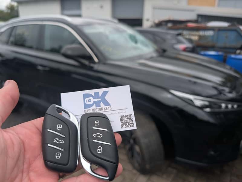 Two freshly cut Audi replacement keys with a Darlington Keys business card