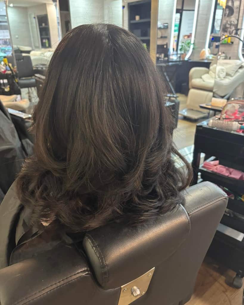 Mid-length deep-brown hair styled with soft curls