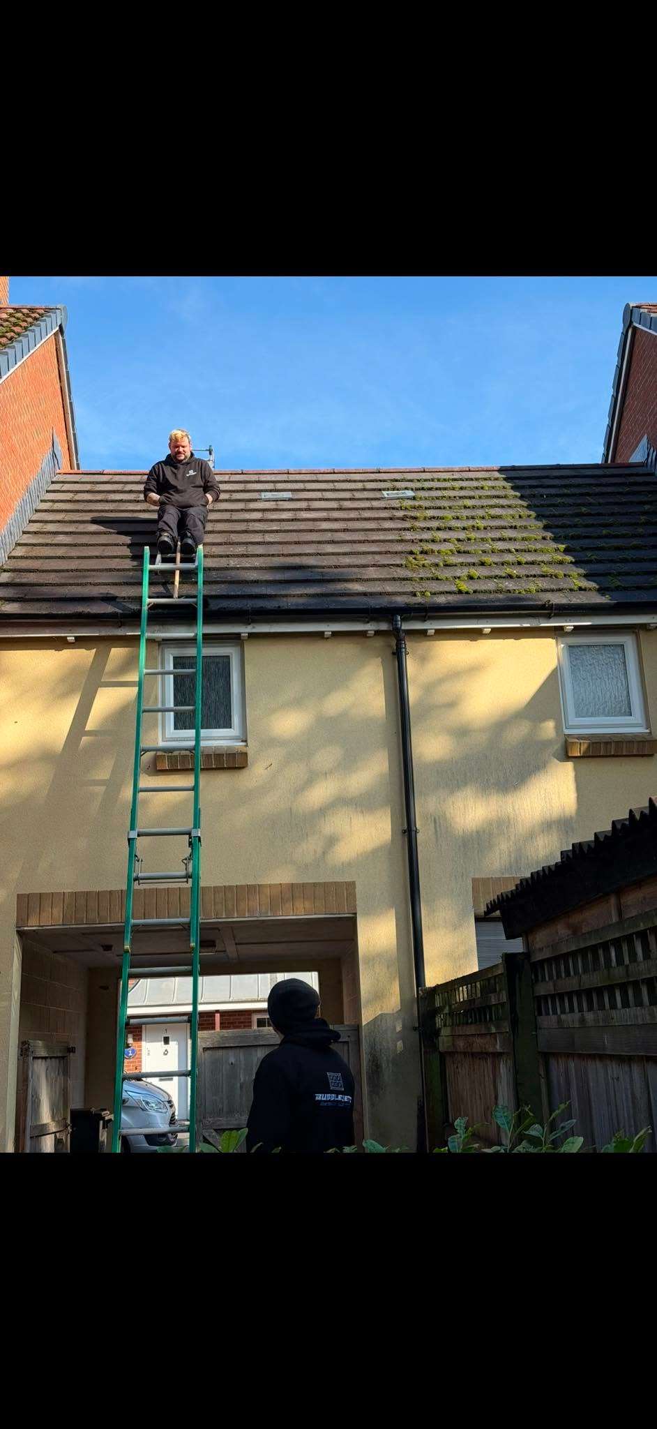 Cleaner on a ladder treating stained render on a house exterior