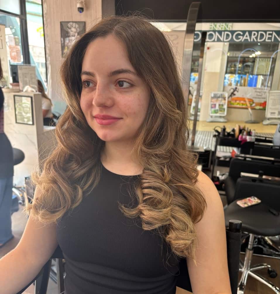 Smiling client with long brown curls after a styling appointment