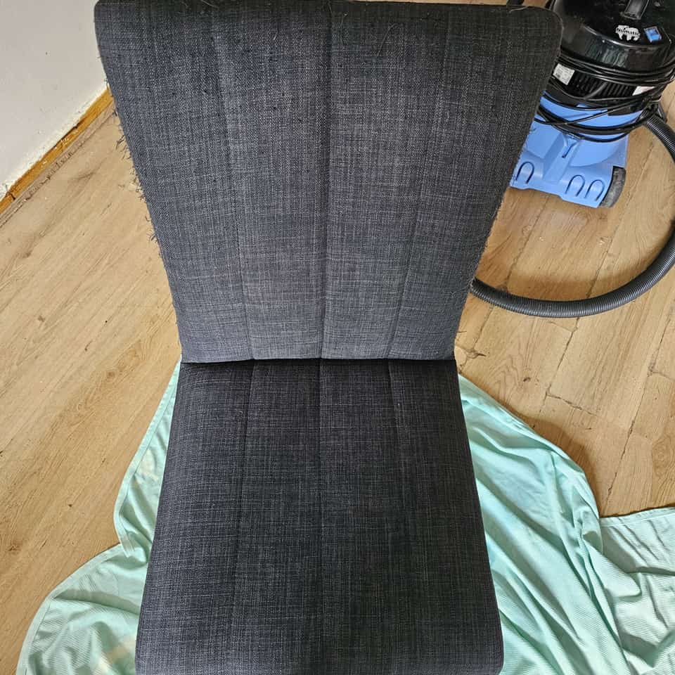 Clean grey upholstered dining chair after cleaning, with a vacuum nearby.