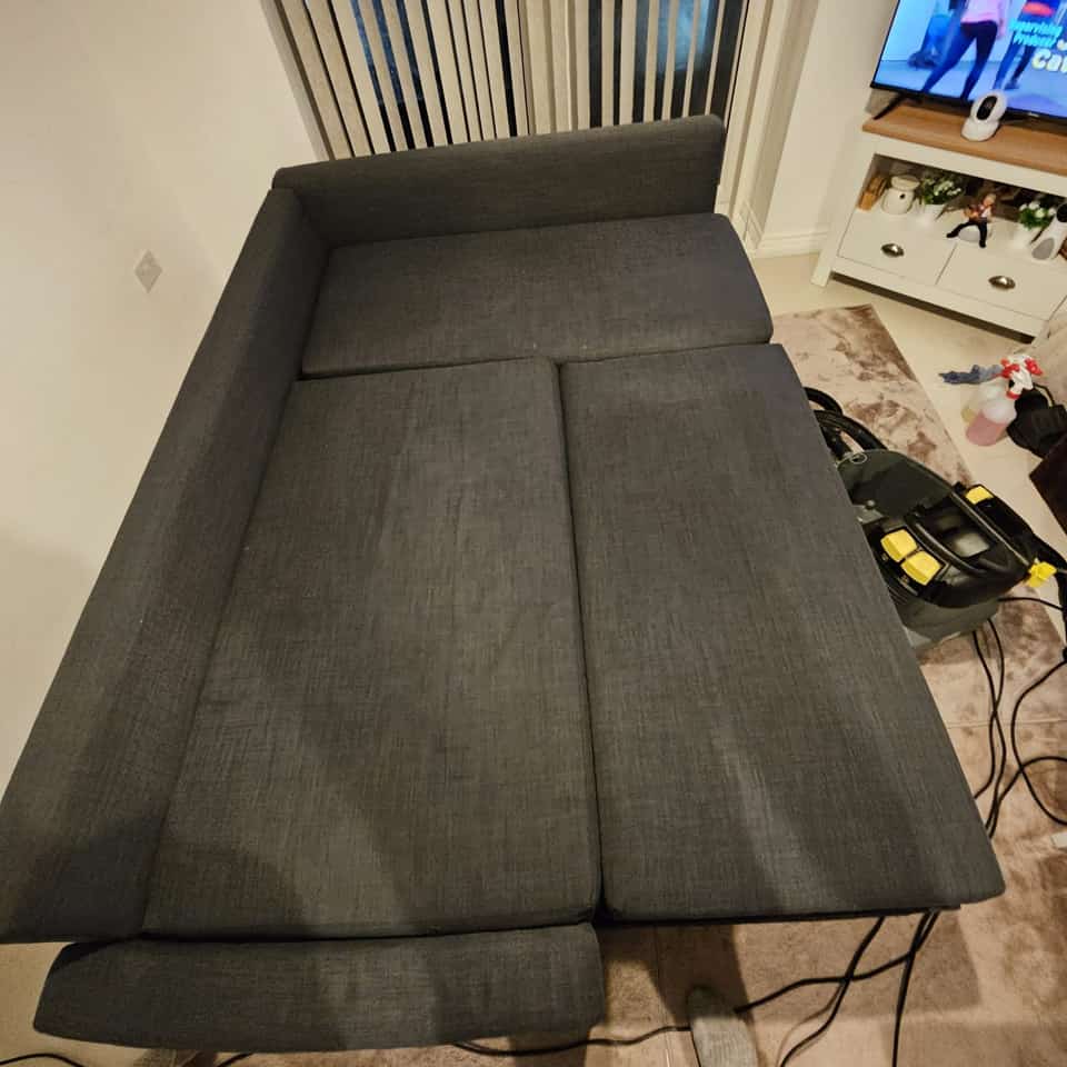 Clean grey fabric sofa bed after upholstery cleaning in a living room.