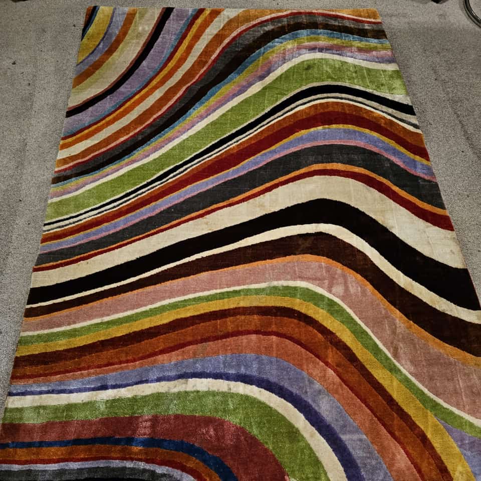 Vibrant striped wave-patterned rug with bright colours restored after cleaning.