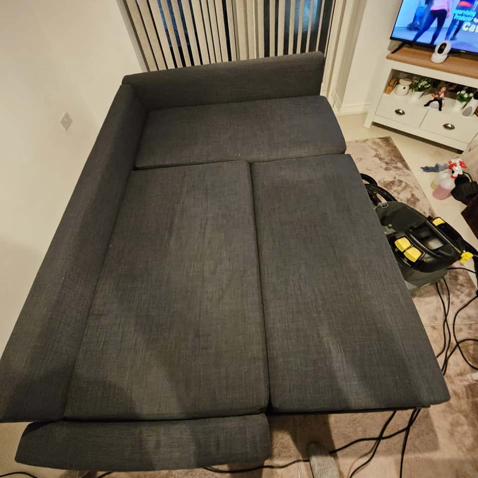 Clean grey fabric sofa bed after upholstery cleaning in a living room.