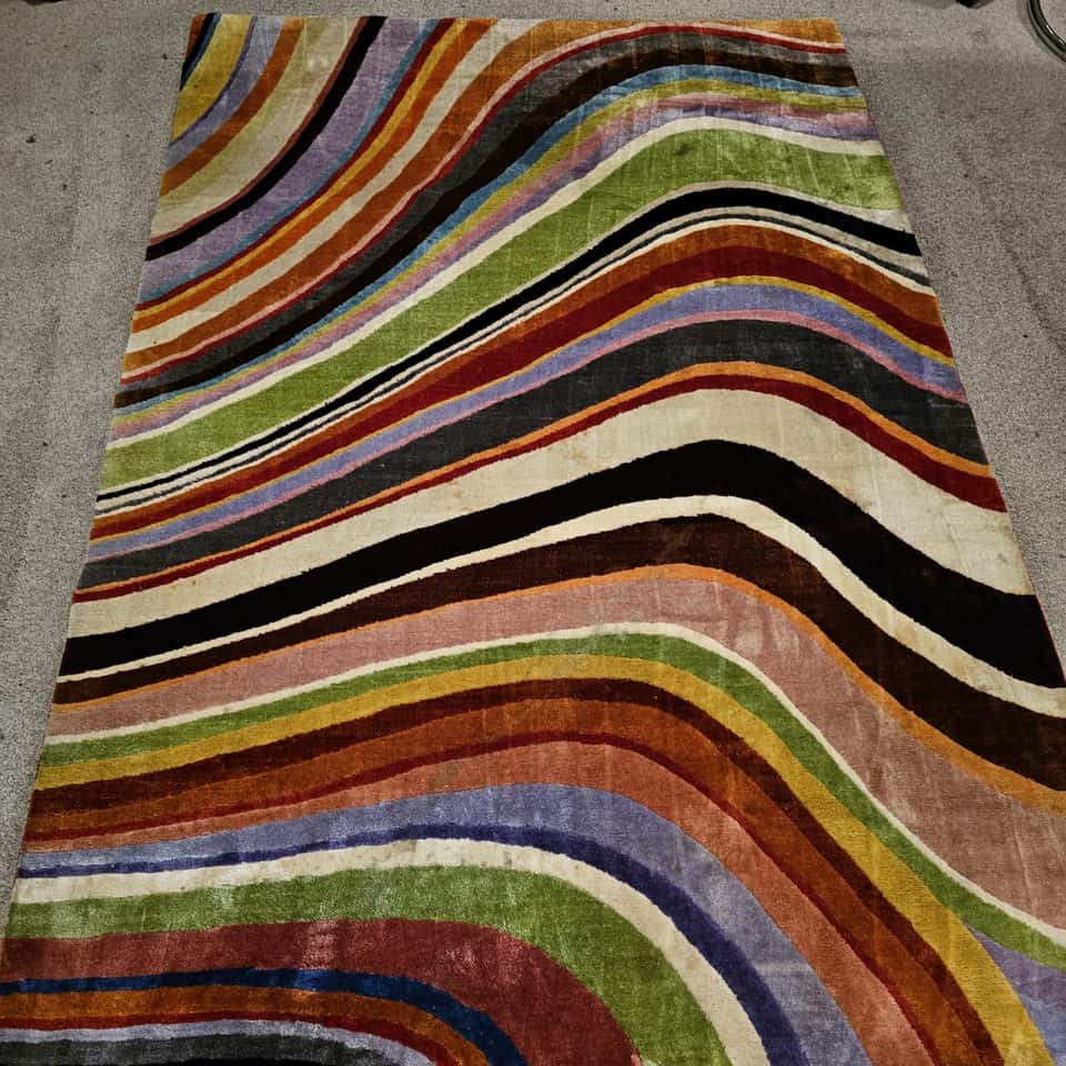 Vibrant striped wave-patterned rug with bright colours restored after cleaning.