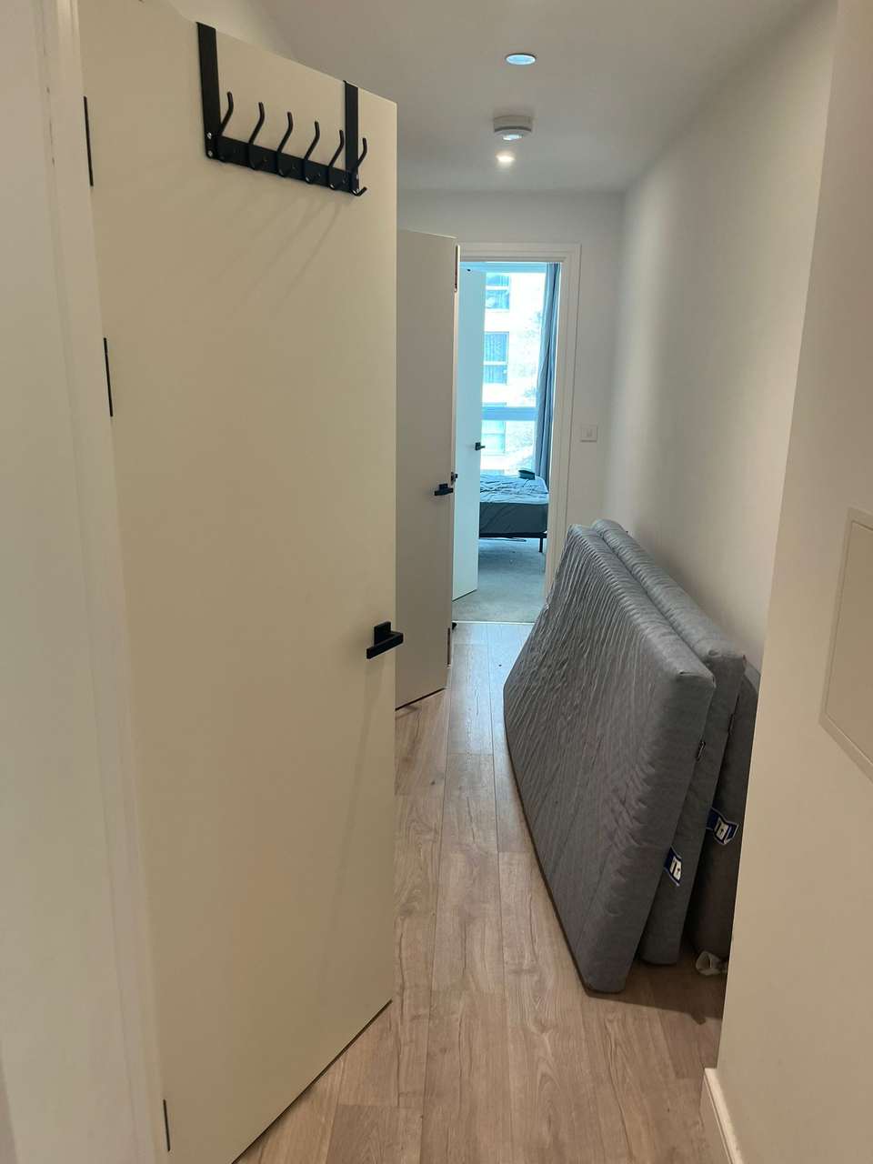 Empty flat hallway with laminate flooring and mattresses ready for an end-of-tenancy clean