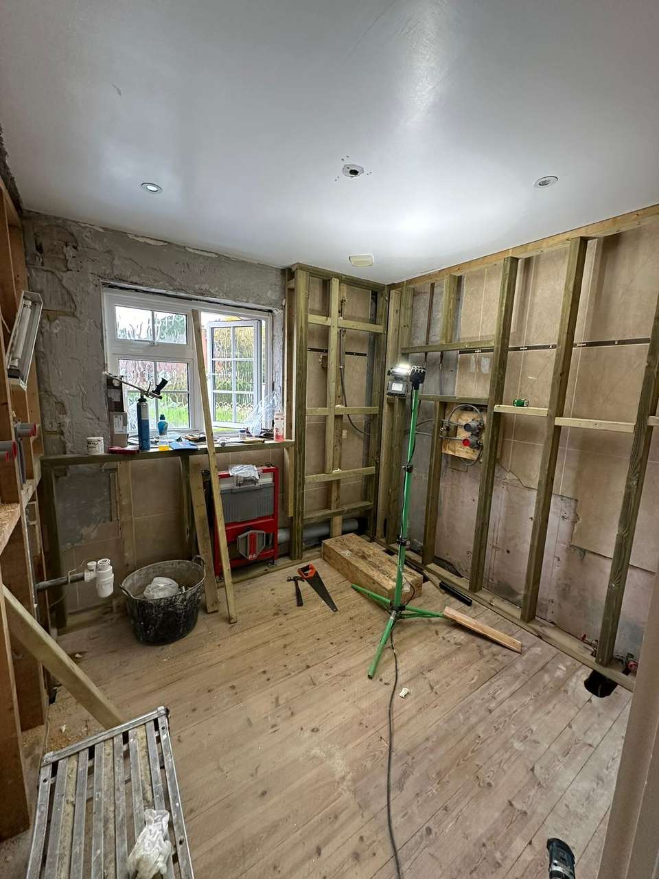 Bathroom renovation in progress with timber stud walls, wall-hung toilet frame, and shower mixer valve plumbing.