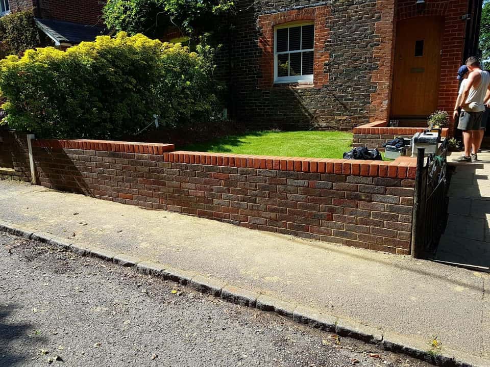 New low front garden brick wall with red soldier-course coping in front of a brick house