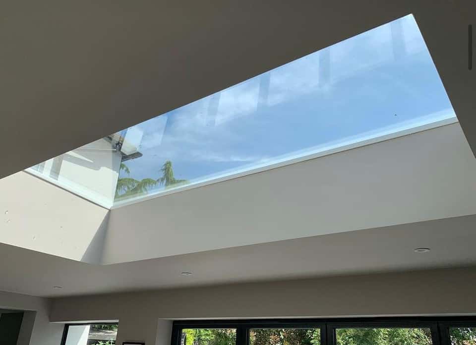Large rectangular roof lantern set into a white plastered ceiling flooding a modern extension with natural light.