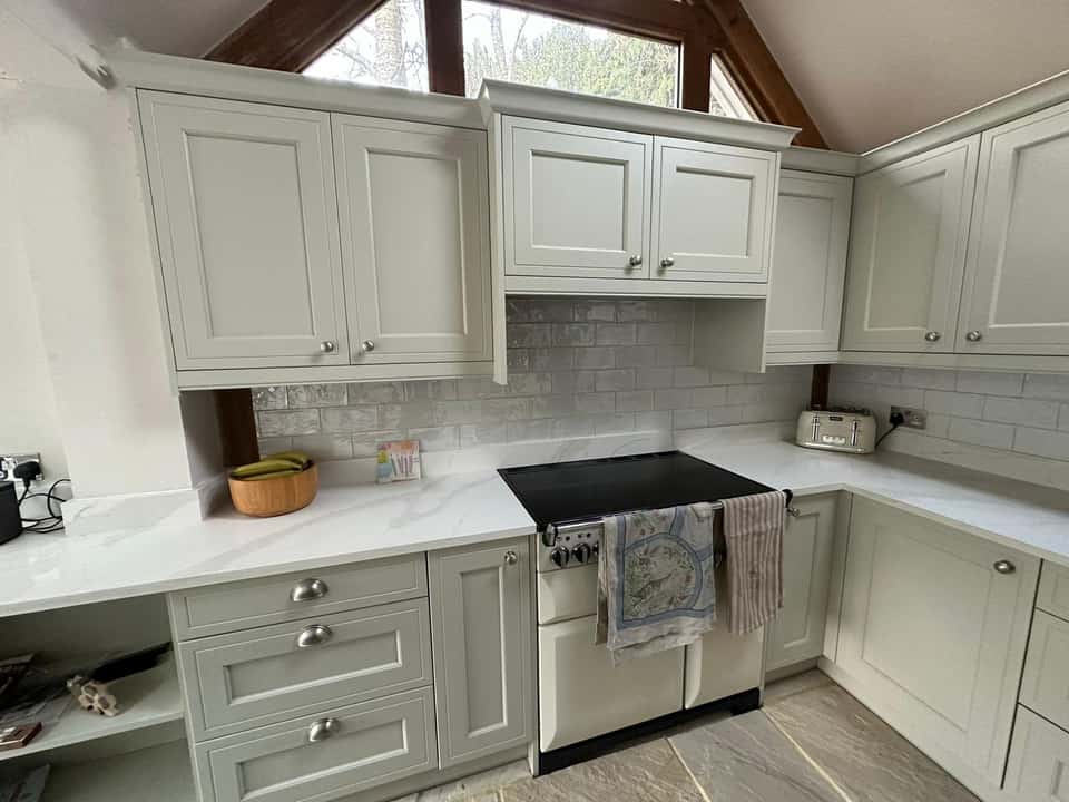 Finished grey Shaker kitchen with cream range cooker, marble quartz worktops, and grey subway tile splashback.