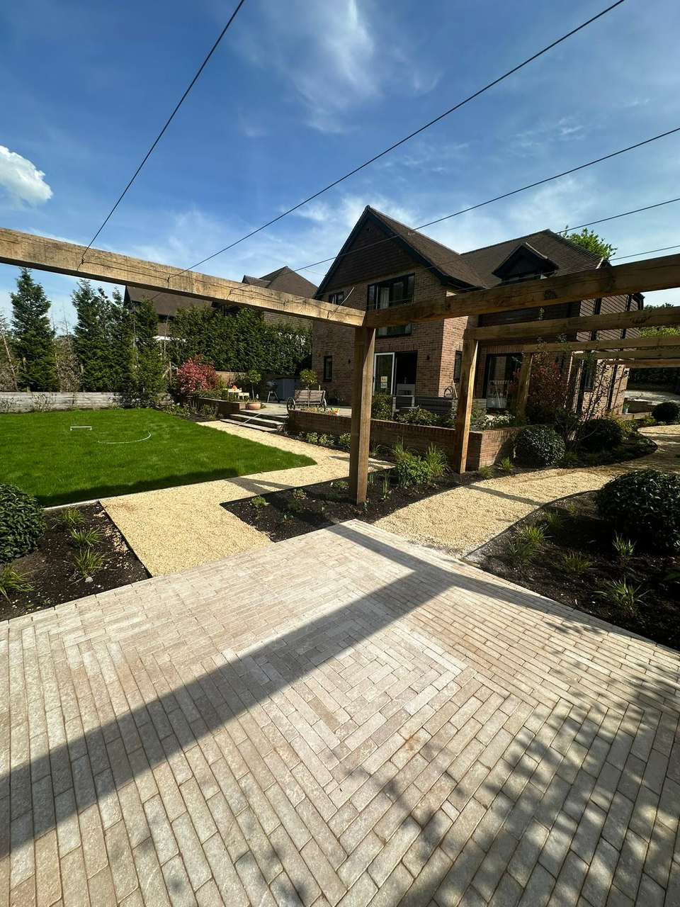 Finished herringbone stone patio with a large timber pergola in a landscaped rear garden