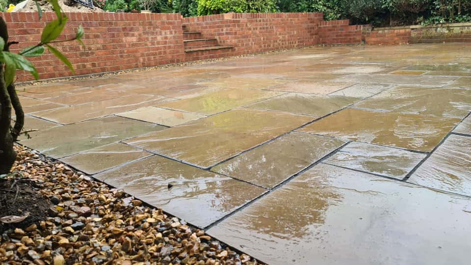 Wet natural stone patio with a red brick retaining wall and integrated garden steps