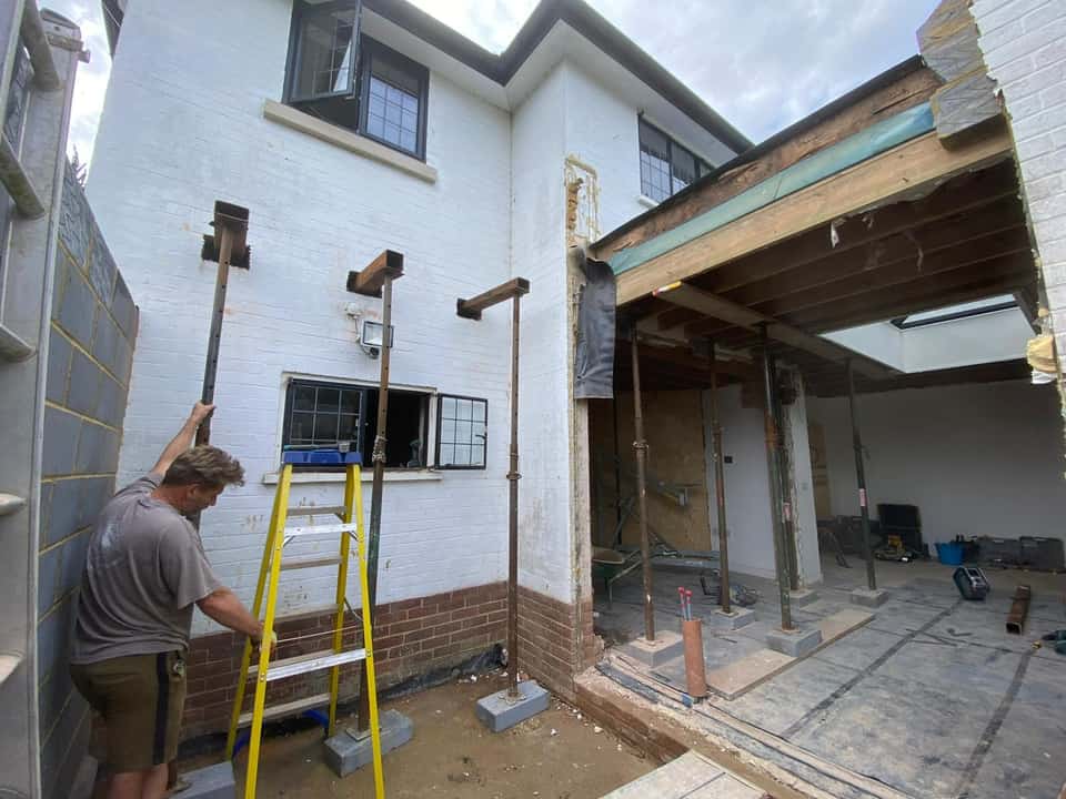 Structural alteration with steel needles and Acrow props supporting a house while a large ground-floor opening is formed.