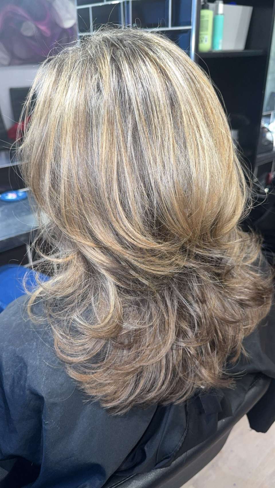 Layered shoulder-length cut with caramel highlights and a glossy bouncy blow-dry finish