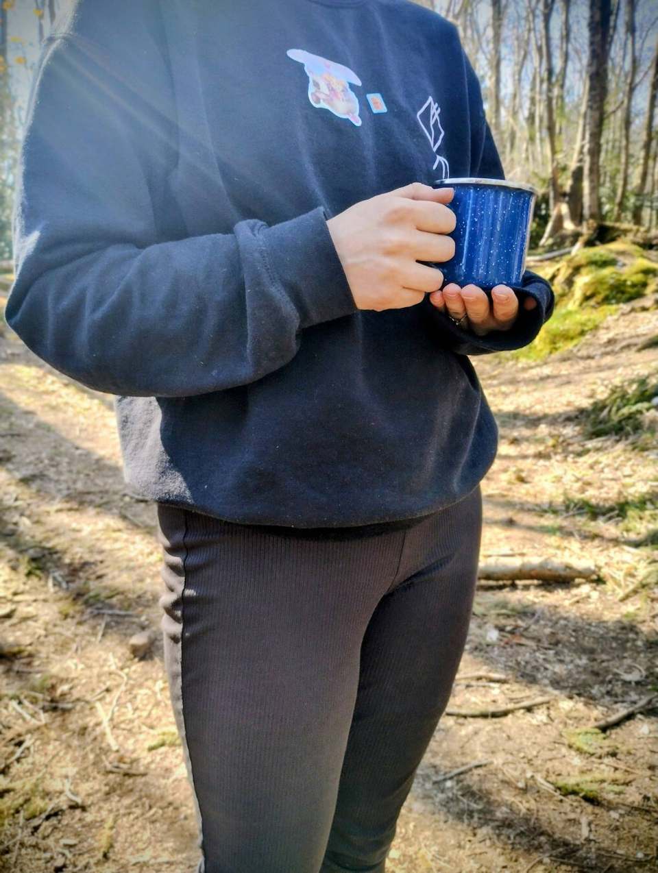 Person in a Beowulf Bushcraft sweatshirt holding an enamel mug