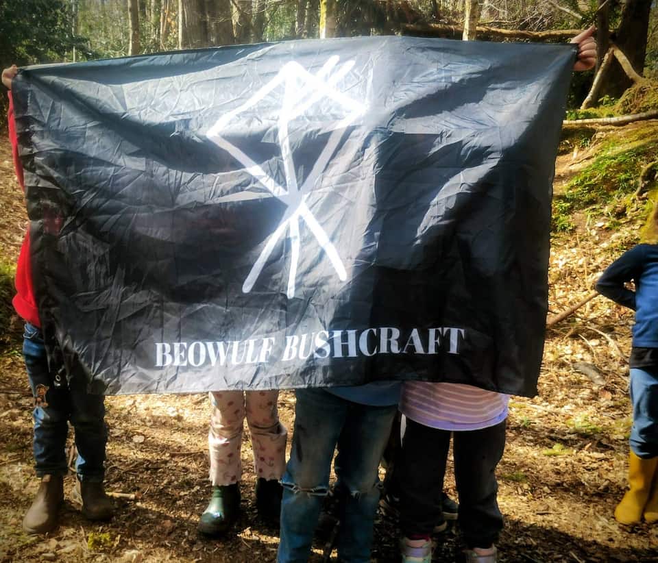 Participants holding the Beowulf Bushcraft flag at Greyfield Woodlands