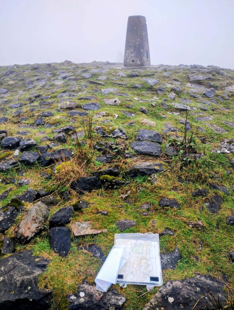 Concrete trig point on a hilltop with a map case