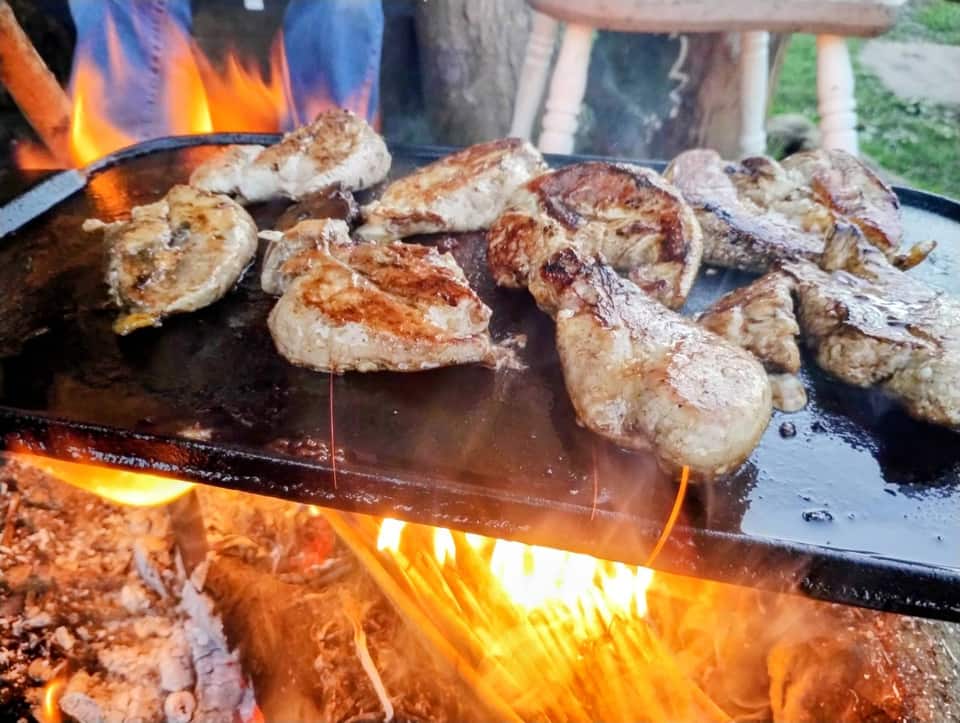 Game meat cooking on a plancha over an open fire