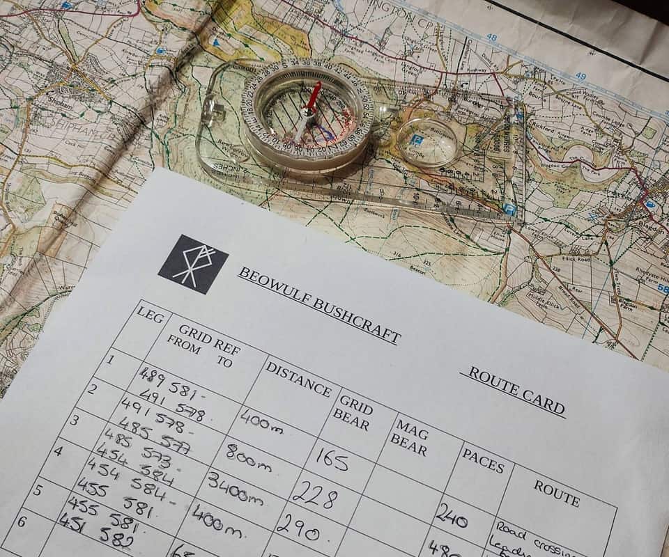 Beowulf Bushcraft route card with compass over an Ordnance Survey map