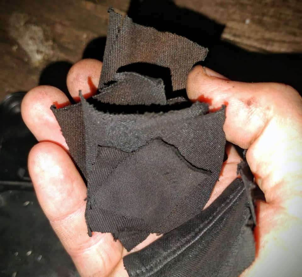 Hand holding a stack of charred char-cloth squares