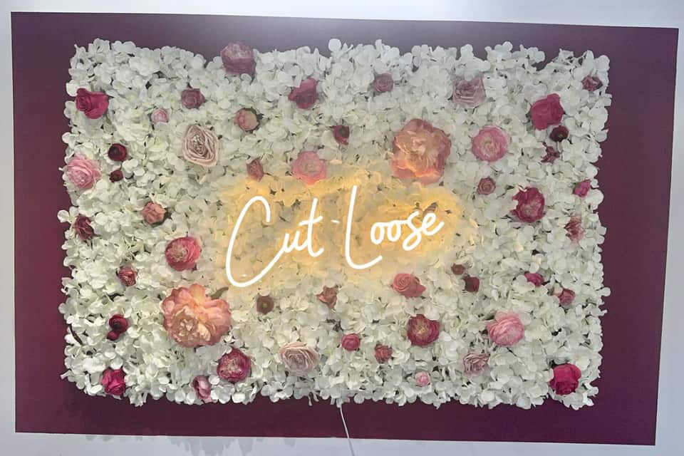 Cut Loose neon sign on the salon’s floral feature wall
