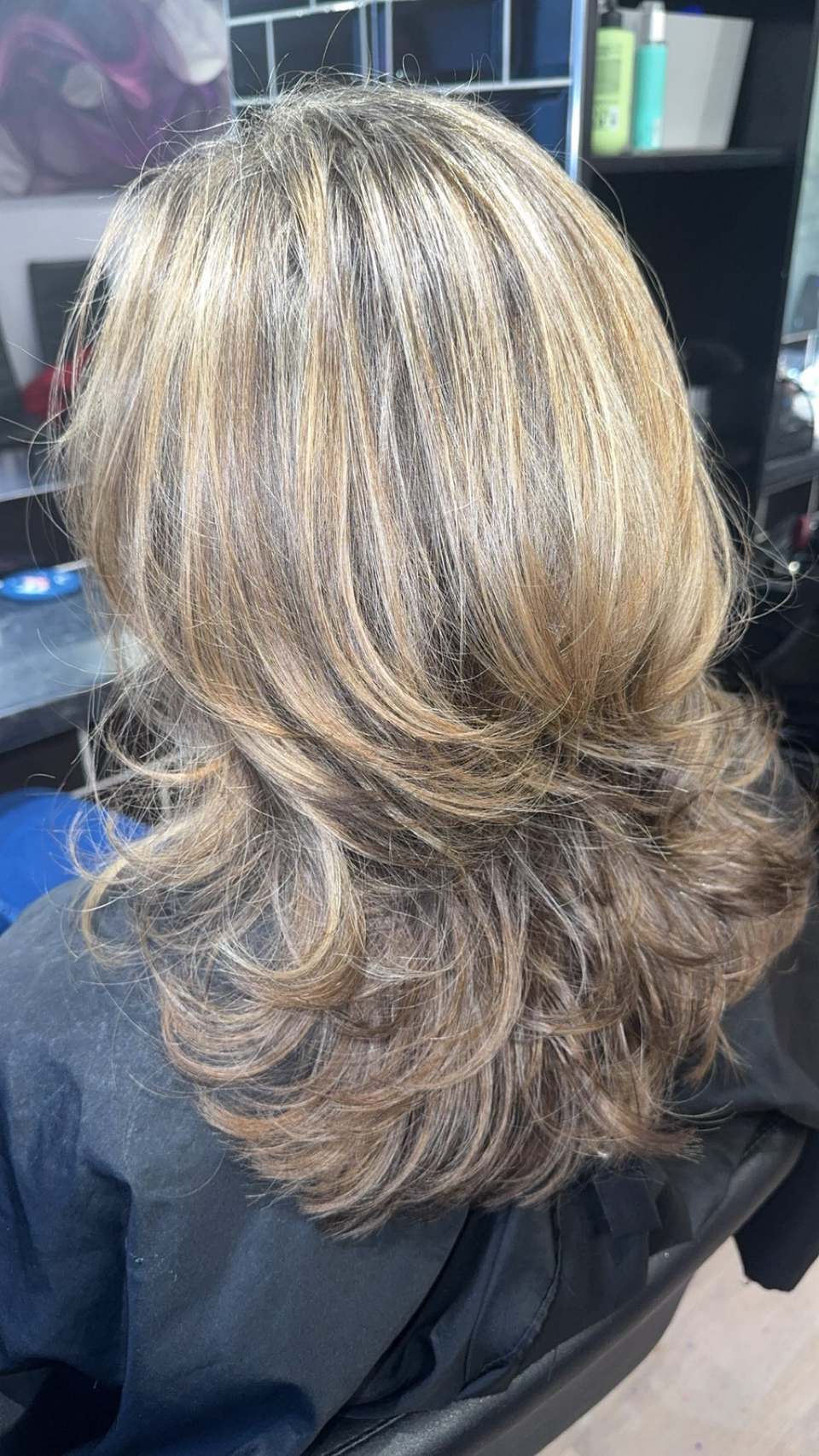 Layered shoulder-length cut with caramel highlights and a glossy bouncy blow-dry finish