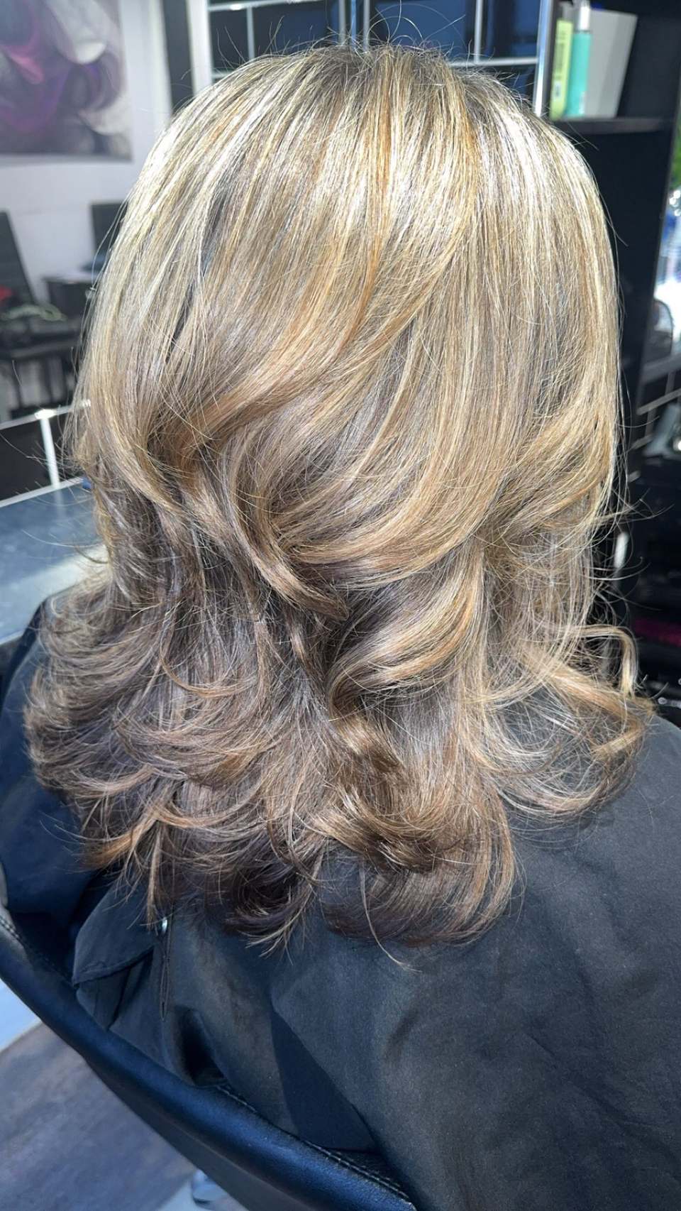 Bouncy curly blow-dry on layered hair with golden highlights