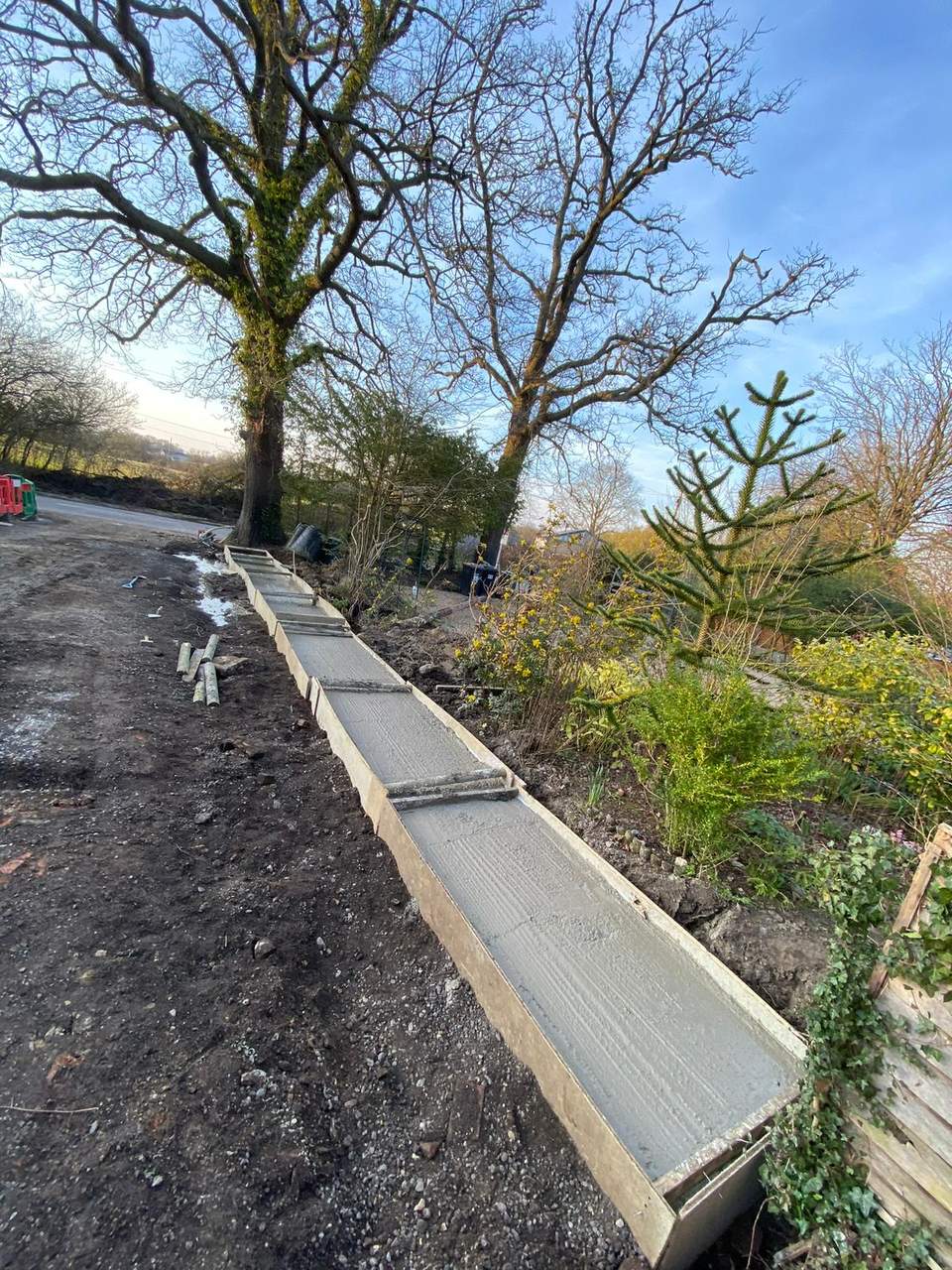 Freshly poured concrete foundation strip in wooden shuttering.