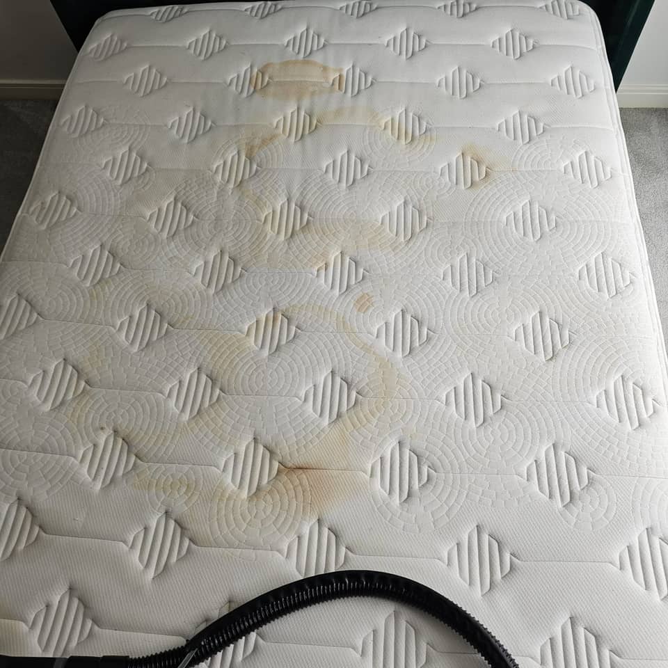 Double mattress with heavy yellow-brown staining before cleaning.