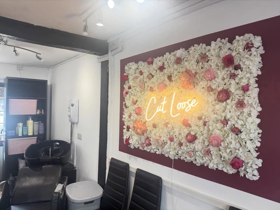 Interior of Cut Loose unisex hair studio showing the floral feature wall and salon styling area