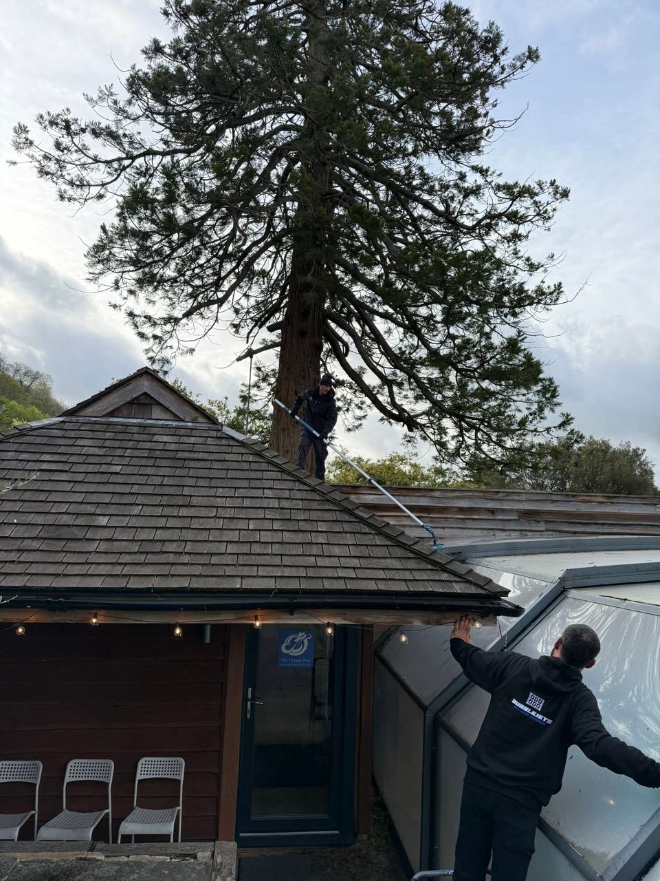 Bubble Jets team in branded hoodies cleaning a glass pool enclosure roof