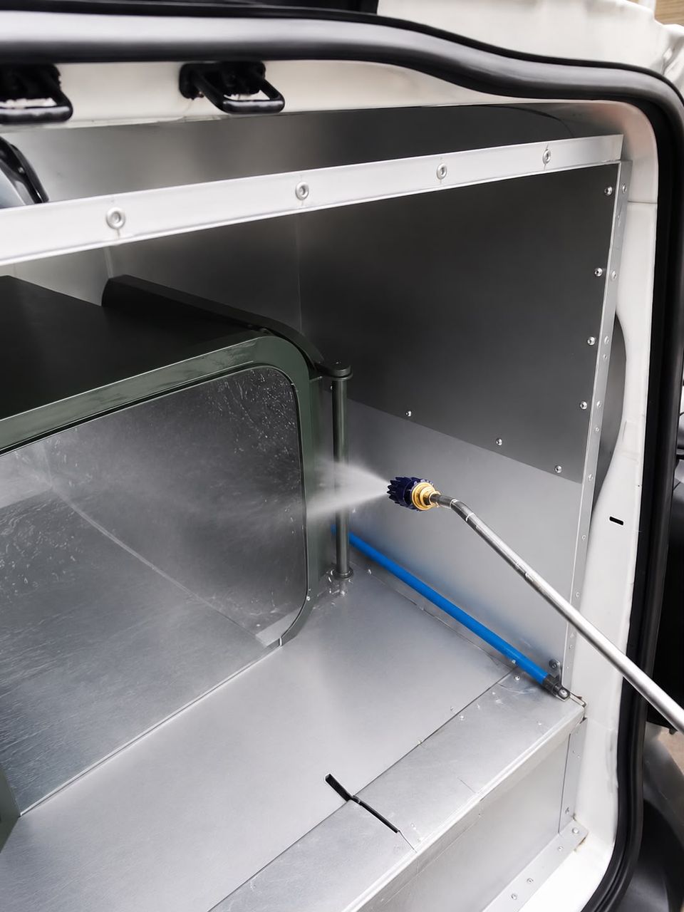 Pressure washer wand in action inside the self-contained wash bay fitted in The BinBusters van